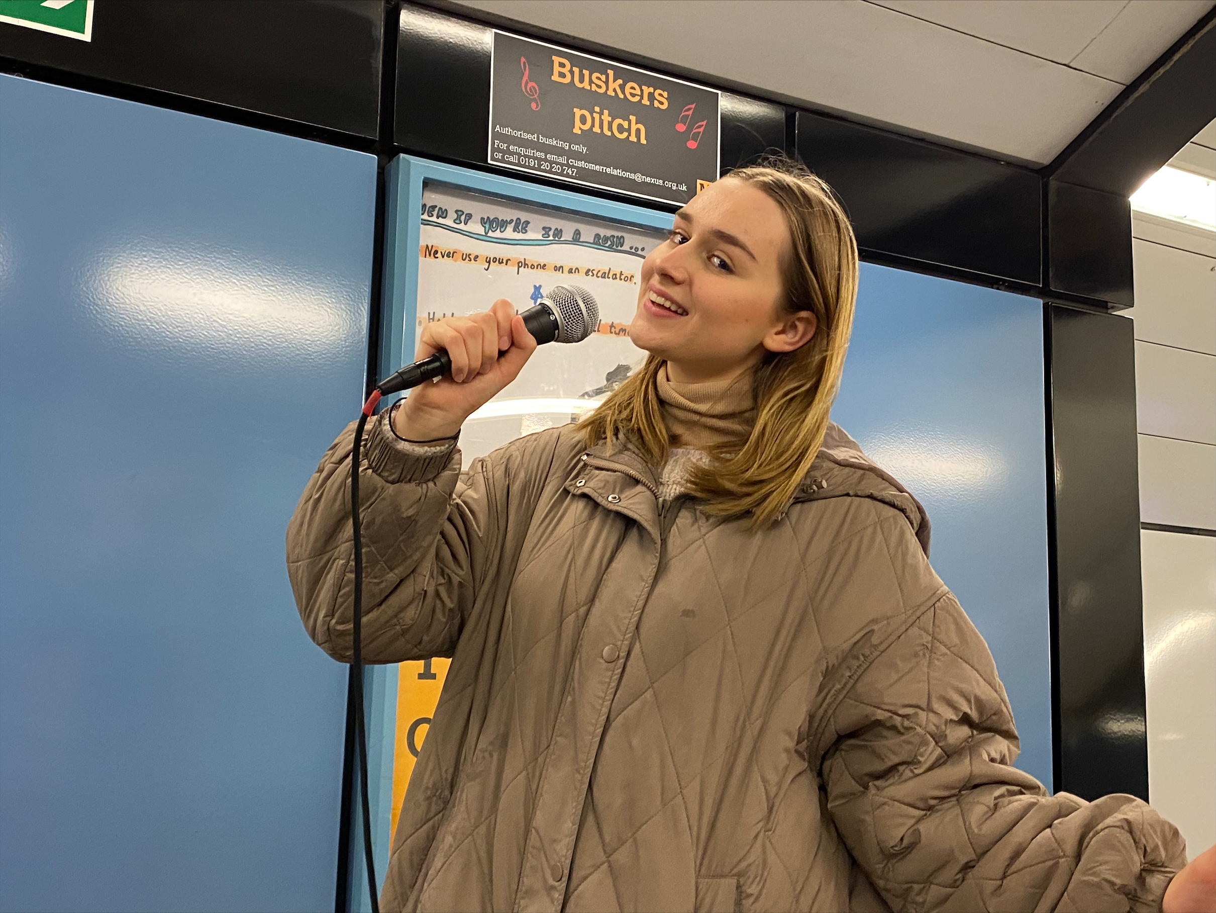 An image of a female singing into a microphone at a Metro station